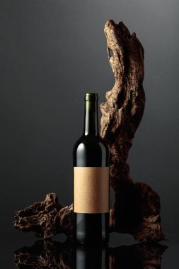 Eski etiketli bir şişe kırmızı şarap. Arka planda eski yıpranmış bir pürüz var. Siyah yansıtıcı arka plan. Metnin için alanı olan ön görünüm.