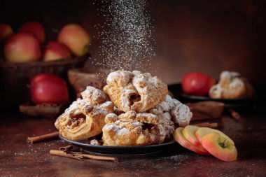 Elma ve tarçınlı ev yapımı mini elmalı turtalar. Üzerine pudra şekeri serpiştirilmiş taze pişmiş yiyecekler. Viyana pastası.