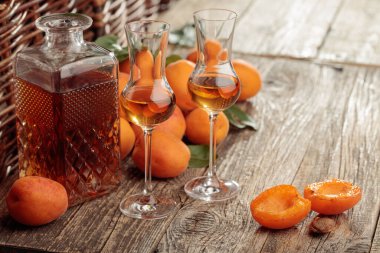 Kayısı likörü ve taze kayısılar eski bir ahşap masada. Kırsal bir arka planda şarap ve sulu meyveler. 