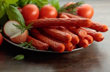 Eski ahşap bir masada fesleğenli ve domatesli Kabanos sosisi..