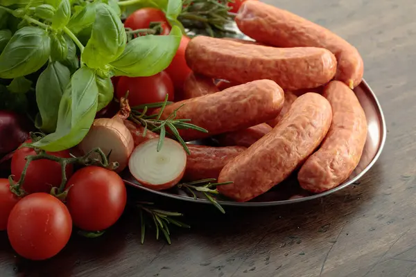 Eski ahşap bir masada fesleğen ve domatesli sosisler..