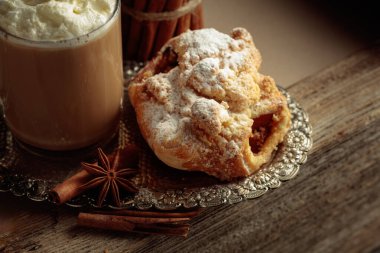 Gümüş tepside Viyana usulü turta ve sütlü kahve. Anason ve tarçınlı taze hamur tatlısı üzerine şeker serpiştirilmiş..