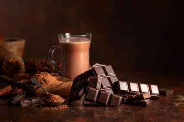 Kahverengi bir şarap masasında acı çikolata ve bir bardak kakao. Boşluğu kopyala.