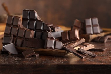 Kahverengi bir arka planda kırık acı ve sütlü çikolatalar..