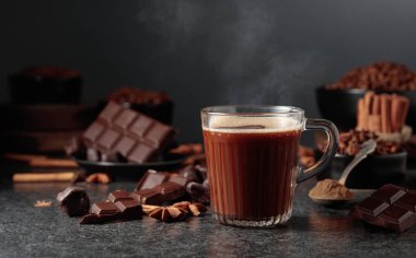 Siyah mutfak masasının üzerinde malzemeler olan bir bardak sıcak çikolata. Boşluğu kopyala.