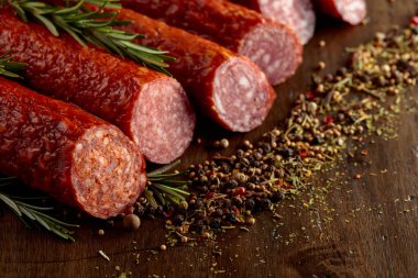 Tütsülenmiş ve kurutulmuş sosis, biberiye ve baharatlar eski ahşap bir masada..