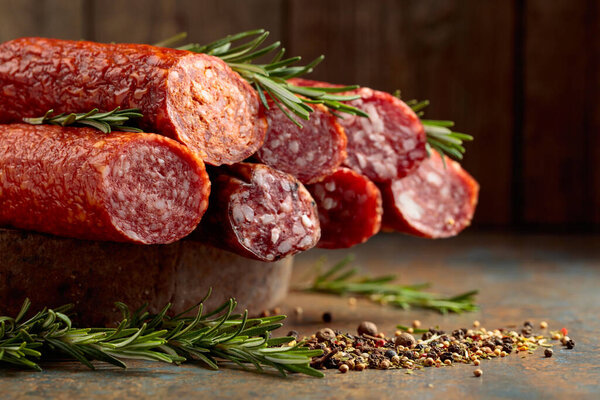 Smoked and dry cured sausages with rosemary and spices on a rustic background.