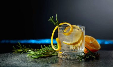 Siyah arka planda limon ve biberiyeli cin tonik kokteyli. Boşluğu kopyala.