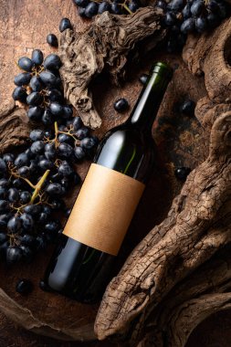 Bir şişe kırmızı şarap, mavi üzümler ve yıpranmış eski parçalar. Eski boş bir şişede. Metninizi etikete yerleştirin.