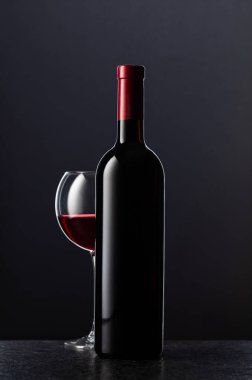 Siyah arka planda bir şişe kırmızı şarap..