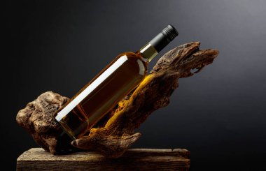 Eski bir pürüzün üzerinde bir şişe beyaz şarap. Ürün markalaşması, kimlik ve ambalaj için siyah arkaplan üzerine minimalist kompozisyon. Boşluğu kopyala.