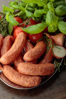 Eski ahşap bir masada fesleğen ve domatesli sosisler..