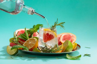 Buzlu, narenciyeli, biberiyeli ve naneli kokteyl. Cin veya rom şişeden bardağa dökülür. Kopyalama alanı olan yeşil arkaplan.