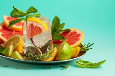 Buz, narenciye, biberiye ve naneli ferahlatıcı bir yaz içeceği. Kopyalama alanı olan yeşil arkaplan.