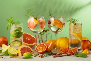 Beyaz mermer bir masada malzemelerle yaz kokteyllerini tazeliyorum. Mojito ve yeşil arka planda çeşitli cin tonik kokteylleri..