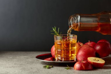 Elma suyu şişeden bardağa dökülür. Eski bir mutfak masasında elmalı taze içecek. Boşluğu kopyala.