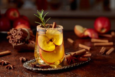 Elma dilimli elma şarabı ve biberiye dalı. Bardak şeker ve tarçın tozuyla süslenmiş..