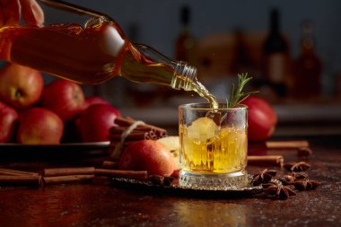 Elma şarabı şişeden kristal bardağa dökülür. Eski bir mutfak masasında elmalı taze içecek. Boşluğu kopyala.