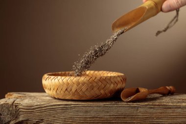 Chia tohumları hasır bir kaseye dökülür. Kopyalama için arkaplan.