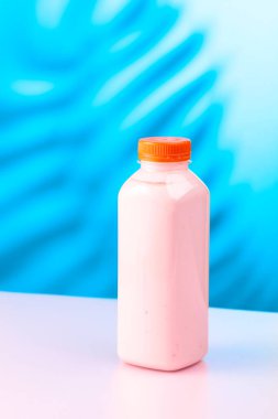 Çilekli milkshake smoothie, eko harcanabilir kavanoz ve taze böğürtlen. Meyve suyu, vitamin içeceği ya da renkli bir arka planda plastik şişede yoğurt. Boşluğu kopyala.