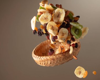 Çeşitli fındıklı kurutulmuş tropikal meyveler ve bej arka planda hareketli kuru üzümler. Boşluğu kopyala.