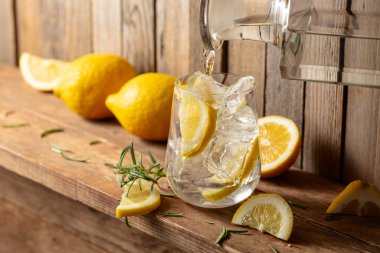 Eski ahşap bir masada buzlu, biberiyeli ve limonlu yaz ferahlatıcı bir içecek. Taze, sağlıklı, soğuk limon suyu. Buzlu ve limonlu su.