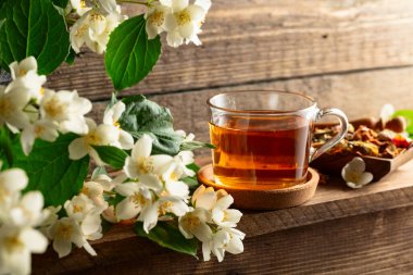 Bir fincan yasemin çayı ve ahşap masada taze yasemin çiçekleri..