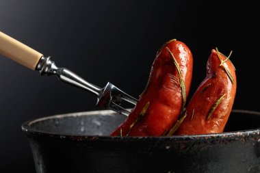 Eski siyah bir tavada biberiyeli kızarmış Bavyera sosisi. Boşluğu kopyala.