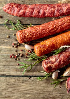 Biber, kekik, biberiye, soğan ve eski ahşap bir masada sarımsaklı çeşitli kurutulmuş sosisler. Üst Manzara. Boşluğu kopyala.