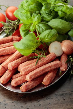 Eski ahşap bir masada fesleğen ve domatesli sosisler..