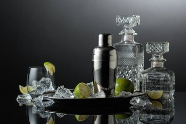 Kokteyl yapımında kullanılan malzemelerle karıştırıcı. Siyah yansıtıcı arka planda ezilmiş buz, limon ve votka sürahisi. Boşluğu kopyala.