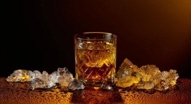 Viski ve buz, siyah ıslak bir masada. Sarı ışık, boşluğu kopyala.