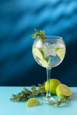 Kokteyller, buzlu cin tonik ve mavi arka planda limon dilimleri. Boşluğu kopyala.