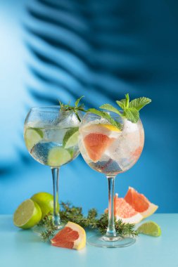 Kokteyller cin tonik, greyfurt ve mavi arka planda limon dilimleri. Boşluğu kopyala.
