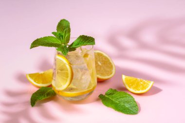 Buzlu, limonlu ve naneli yaz ferahlatıcı içecek. Kopyalamak için pembe arkaplan.