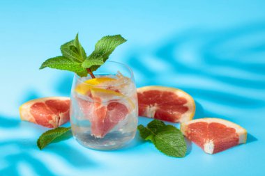 Buzlu, pembe greyfurtlu ve naneli yaz ferahlatıcı içecek. Kopyalama alanı olan mavi arkaplan.