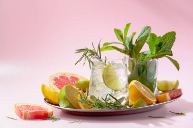 Buz, narenciye, biberiye ve naneli ferahlatıcı bir yaz içeceği. Kopya alanı ile pembe arkaplan.