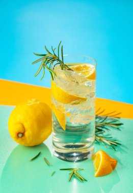 Cin, tonik, limon ve biberiyeyle taze kokteyl. Buzda servis ediliyor, renk ve tazelikle dolup taşıyor. Parlak renkli arkaplan.