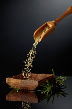 Siyah yansıtıcı arka planda biberiye. Kuru biberiye ahşap bir kaseye dökülür..