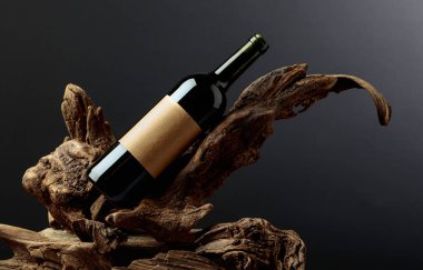 Bir şişe kırmızı şarap ve üzerinde eski bir etiket var. Ürün markalaşması, kimlik ve ambalaj için siyah arkaplan üzerine minimalist kompozisyon. Boşluğu kopyala.