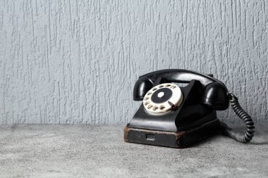 Gri taş bir masada döner tuşlu klasik siyah bir telefon. Boşluğu kopyala.