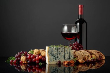 Ciabatta, ceviz, üzüm ve kırmızı şaraplı Gorgonzola peyniri. Geleneksel İtalyan küflü peyniri. Siyah yansıtıcı arka planda meyveler ve aromatik otlar..