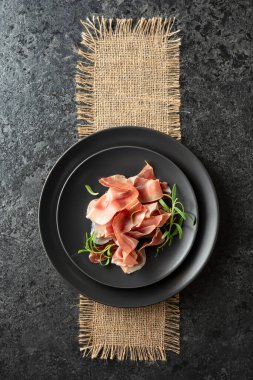 Prosciutto ve biberiye siyah bir masada. Üst görünüm. 