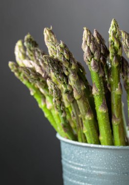 Gri arka planda su damlaları olan taze kuşkonmaz.. 