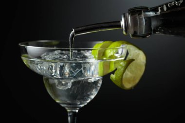 Votka ya da cin buzlu bir bardağa doldurulur. Koyu arkaplanda limon kabuğu olan kokteyl..