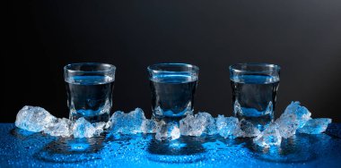 Siyah bir masada votka ve ezilmiş buz. Mavi ışık güzel gölgeler yaratır. Boşluğu kopyala.