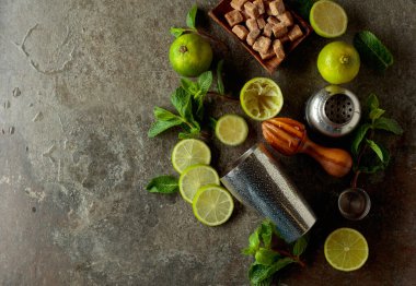 Tahta narenciye sıkacağı, karıştırıcı ve yaz ferahlatıcı içecekler yapmak için malzemeler. Esmer şeker, limon ve taş bir masada taze nane dalları..