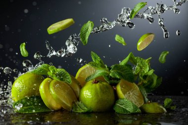 Siyah arka planda limon ve taze nane dalları. Serinletici içecekler ve su sıçraması için gerekli malzemeler. Boşluğu kopyala.