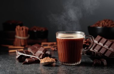 Siyah mutfak masasının üzerinde malzemeler olan bir bardak sıcak çikolata. Boşluğu kopyala.