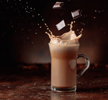 Acı çikolata parçaları cam bardağa dökülür kakao içeceği ile güzel su sıçratır. Boşluğu kopyala.